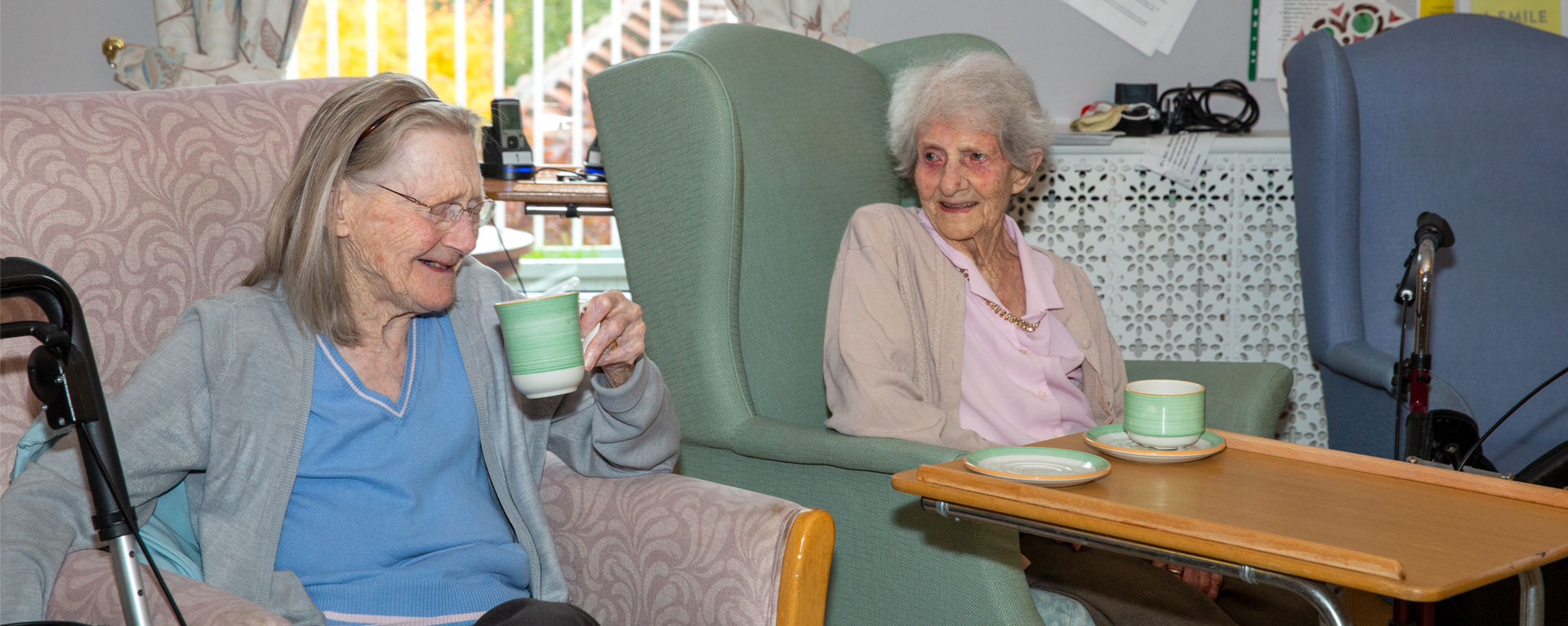 Two residents relaxing in the lounge having a cup of tea