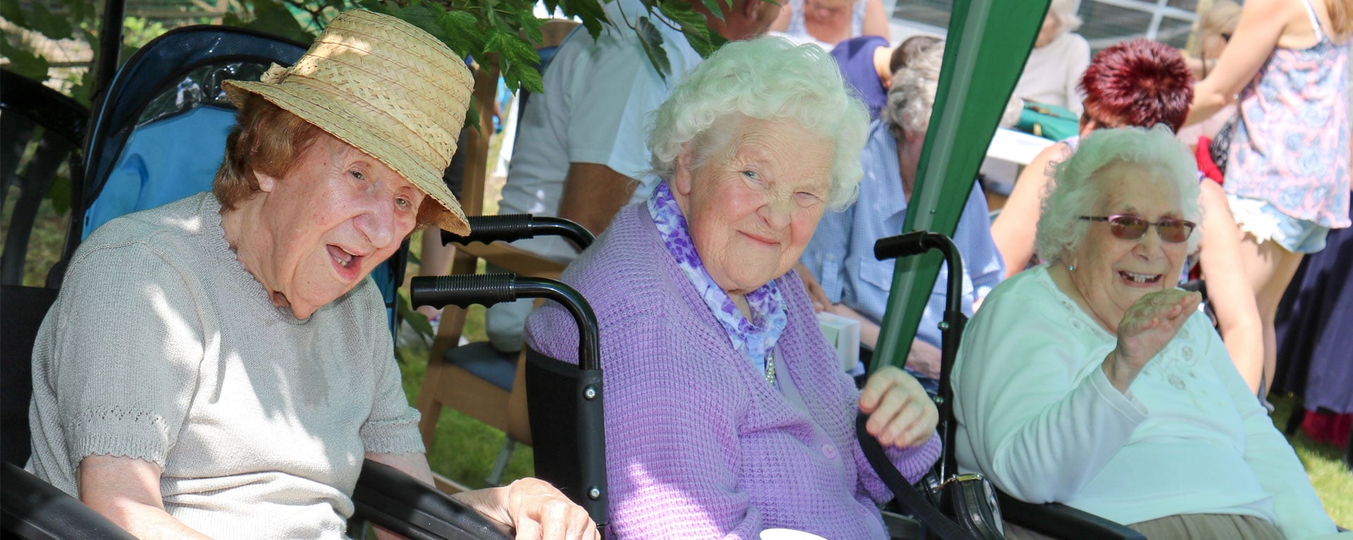 Three residents smiling and laughing at Laurel Care homes summer fete