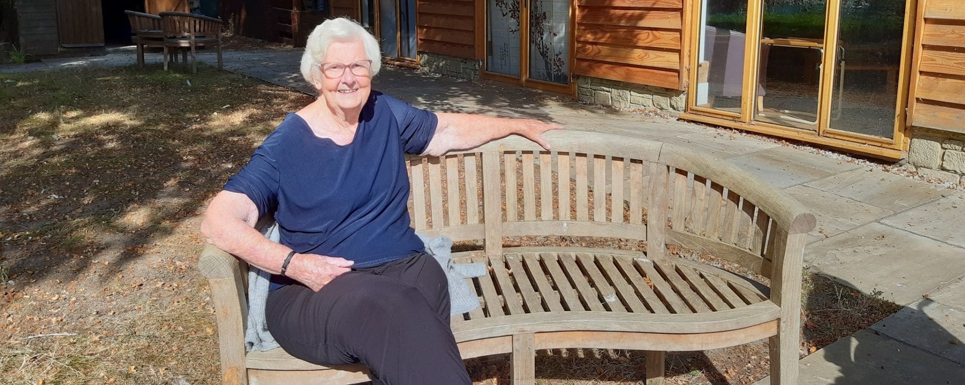 Laurel Care Home resident sat on the bench in the garden on a sunny day